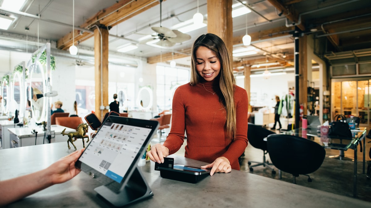 Staff member at the till with a card terminal serving a customer