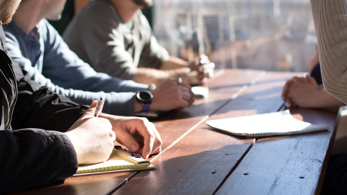Colleagues at a table passing written notes during a discussion