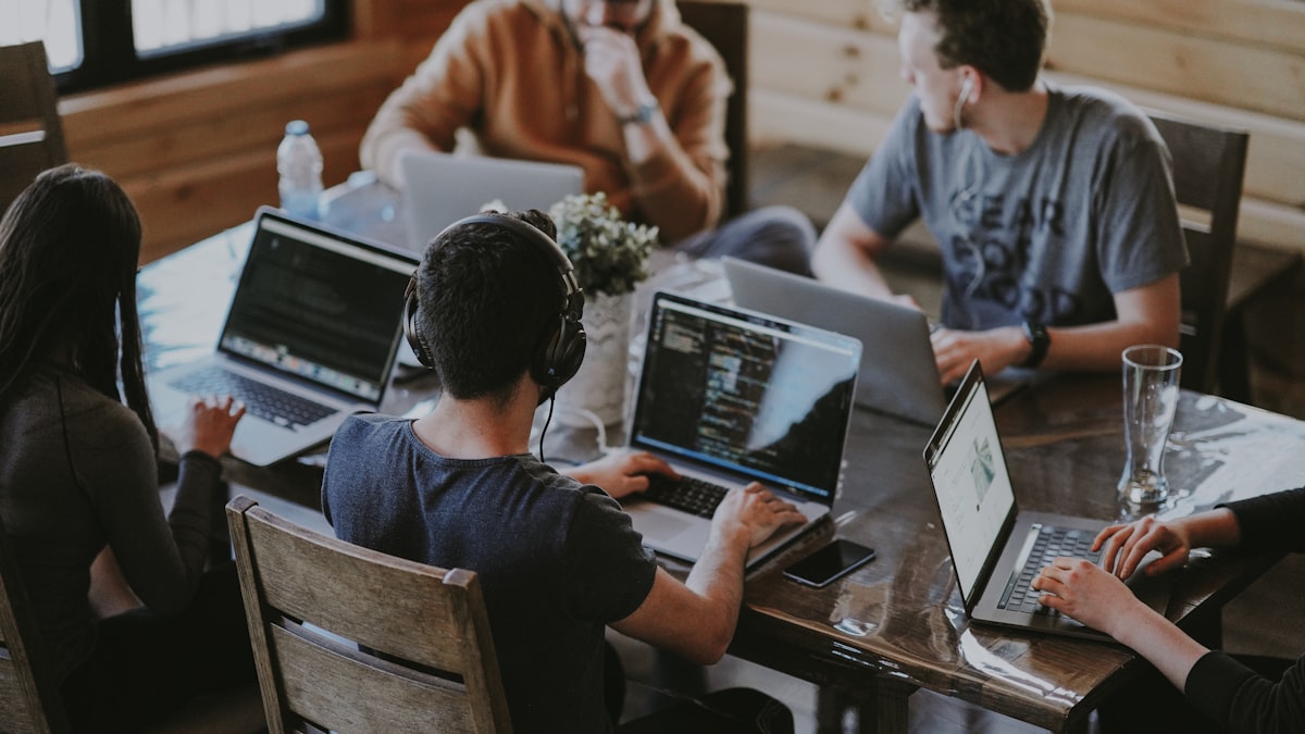 Mixed team working together around a table with laptops
